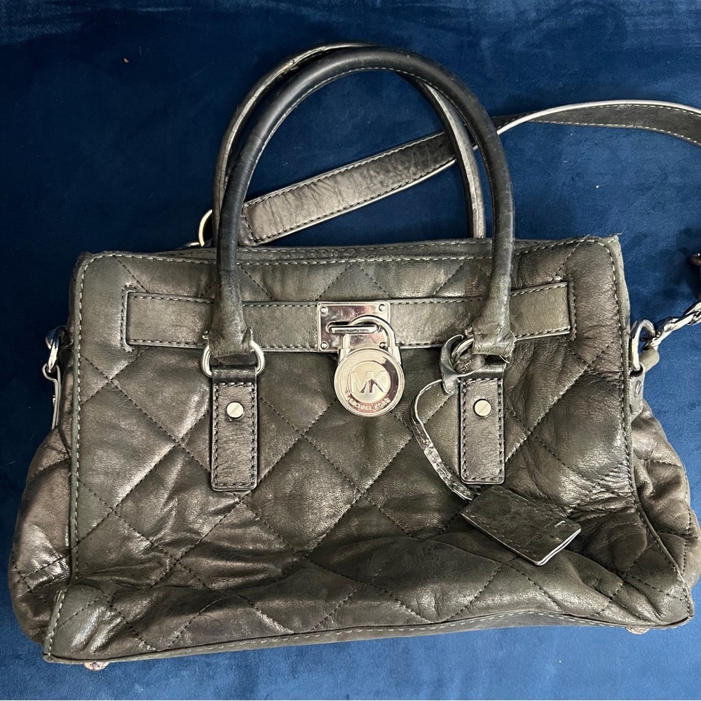 Michael Kors gun metal leather quilted handbag with decorative lock.